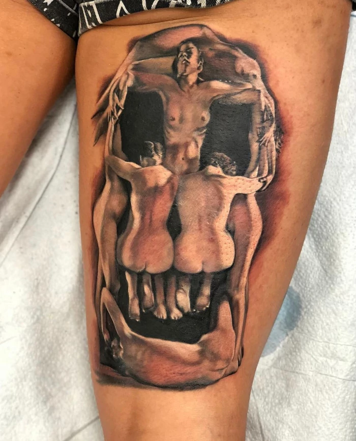 Skull formed of bodies back of thigh tattoo done in black and grey ink by tattoo artist Russ Howie of Sacred Mandala Studio in Durham, NC